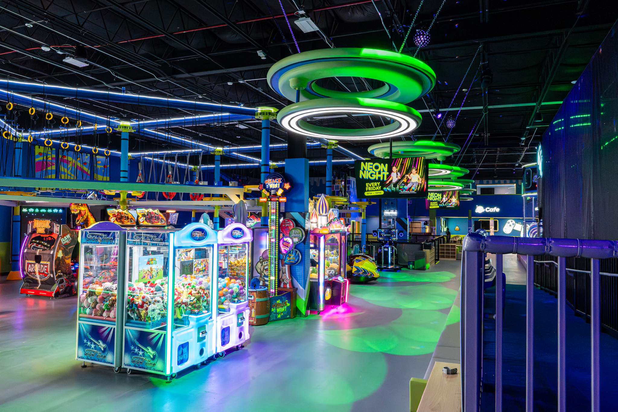 Arcade with claw machines under glowing ring lights at NRG Fargo