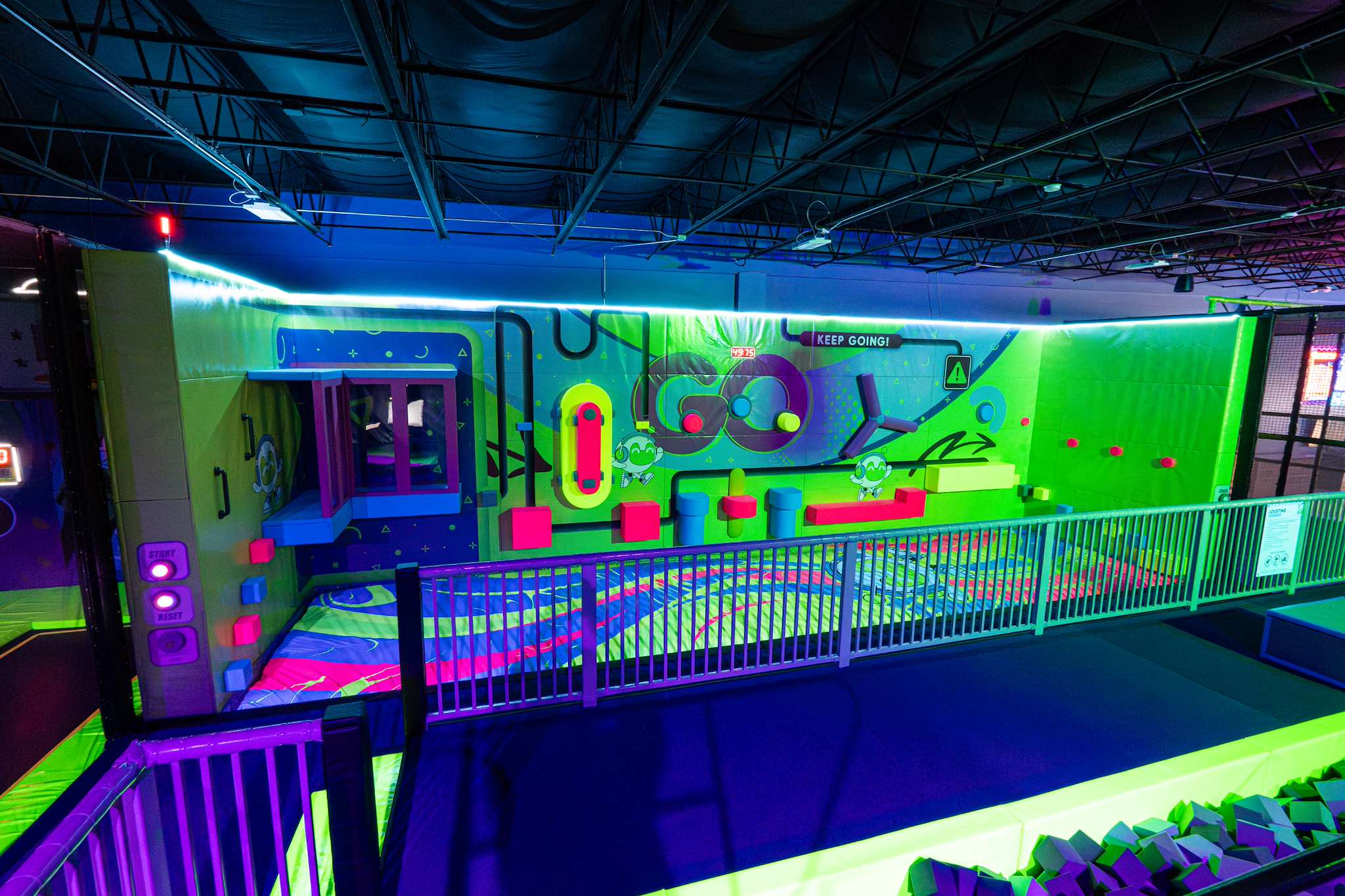 Neon-lit climbing wall above a foam pit at NRG Fargo